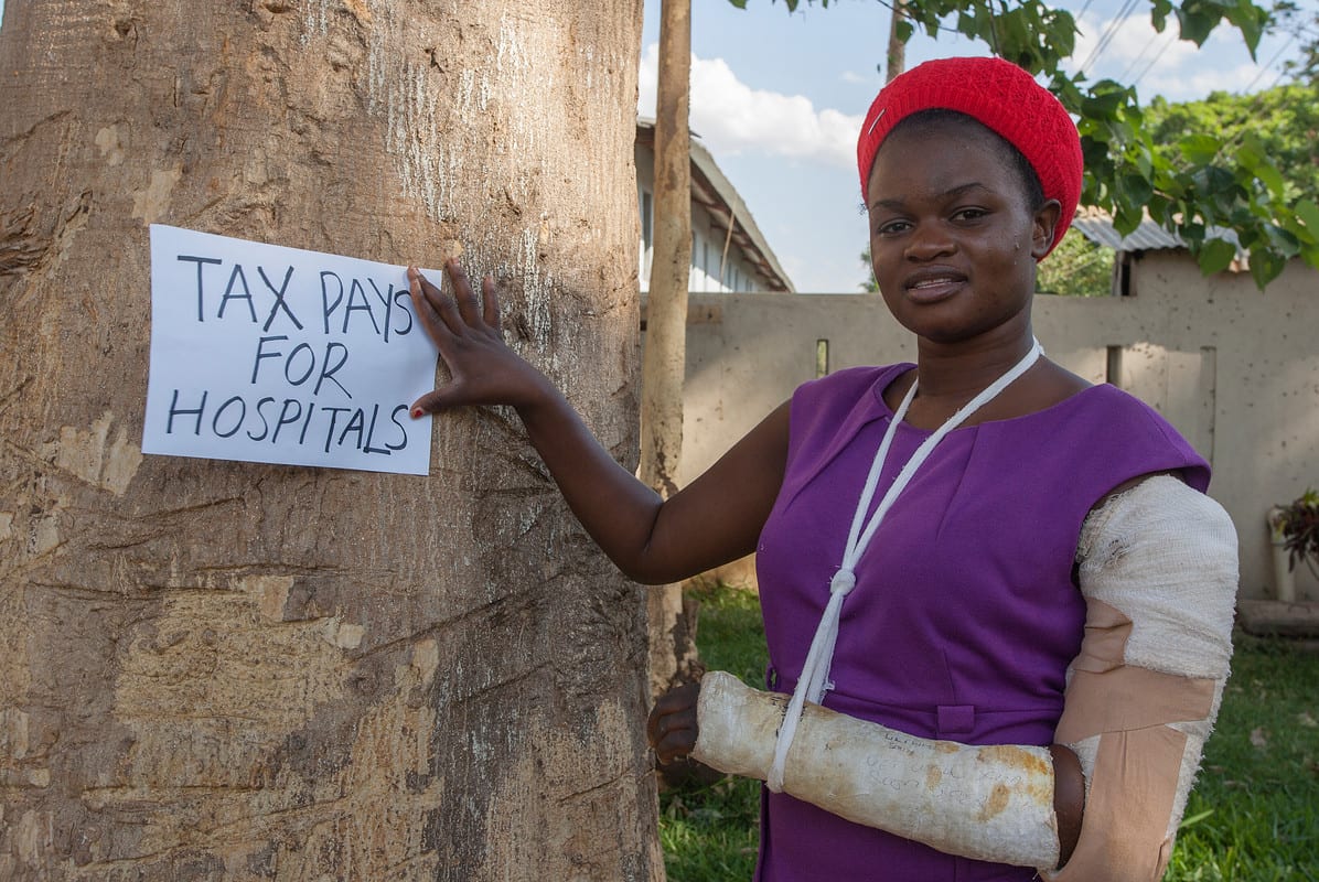 Afrikaanse vrouw met de poster belasting betaalt voor de gezondheidszorg Tax pays for hospitals