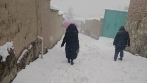 Twee mensen lopen weg van de camera in een steeg die wit is van de sneeuw.