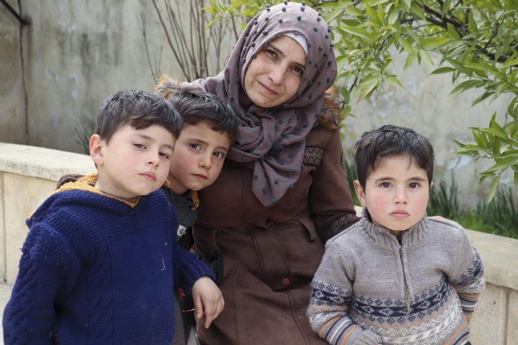 Moeder Noor met haar drie kindjes op de foto in een kamp voor slachtoffers van de aardbeving.