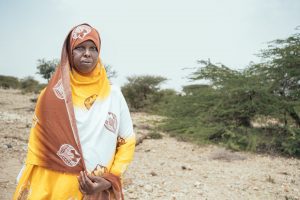 Op de foto staat Sada, een 30-jarige boer in Somaliland. Zij draagt een lange jurk van wit, geel en bruin die ook haar haar bedekt.
